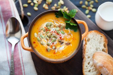 Ahşap bir zemin üzerine krema, ekmek, Yeşiller ve balkabağı tohumları ile ev yapımı balkabağı çorbası. En iyi viev