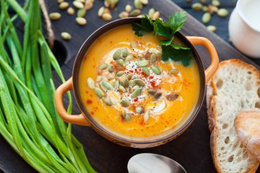 Ahşap bir zemin üzerine krema, ekmek, Yeşiller ve balkabağı tohumları ile ev yapımı balkabağı çorbası. En iyi viev