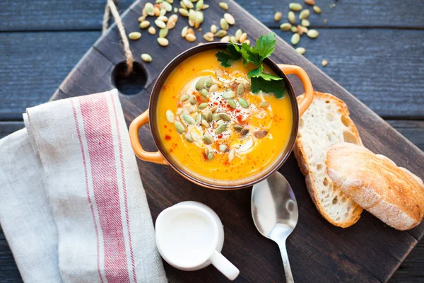 Ahşap bir zemin üzerine krema, ekmek, Yeşiller ve balkabağı tohumları ile ev yapımı balkabağı çorbası. En iyi viev