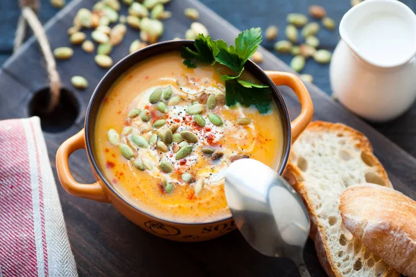 Ahşap bir zemin üzerine krema, ekmek, Yeşiller ve balkabağı tohumları ile ev yapımı balkabağı çorbası. En iyi viev