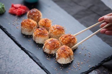 Japon mutfağı. Et ürünleri ve taş levha siyah granit zemin üzerine peynir pişmiş suşi. Üstten Görünüm