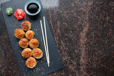 Japon mutfağı. Et ürünleri ve taş levha siyah granit zemin üzerine peynir pişmiş suşi. Kopya alanı ile Üstten Görünüm