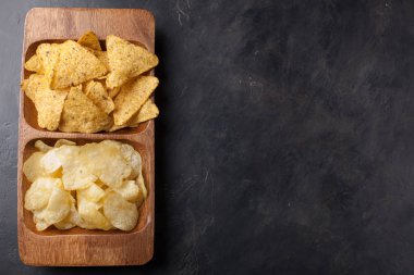 Parti çerez, cips, karanlık beton masa ahşap bir tabağa Nacho. Üstten Görünüm, kopya alanı