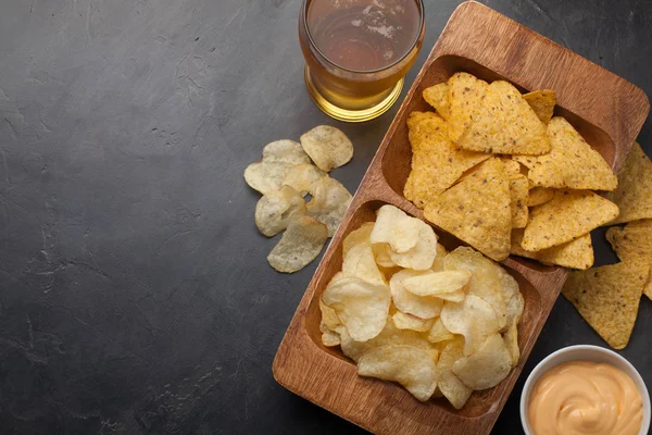 Gözlük closeup beton masada bira. Bira ve aperatifler patates kızartması ve cips peynir sosu ile ahşap kase vardır. Üstten Görünüm. Uzay kopyalayın. İçecek ve aperatif futbol maçı veya parti için
