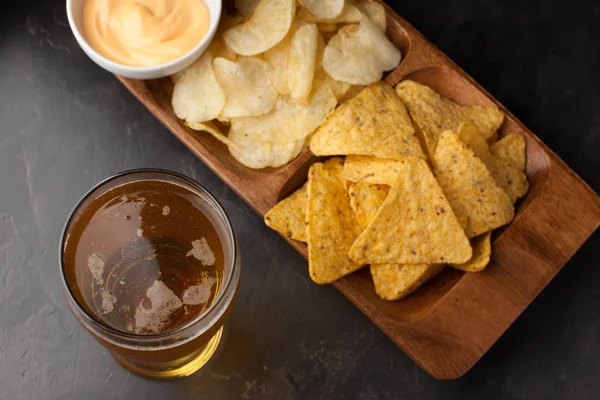 Gözlük closeup beton masada bira. Bira ve aperatifler patates kızartması ve cips peynir sosu en iyi manzaralı vardır. İçecek ve aperatif futbol maçı veya parti için
