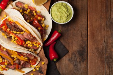 Mermer sığır eti, siyah Angus ve sebze eski rustik masada üç Meksikalı Taco. Soslar guacamole ve salsa kase ile Meksika yemek
