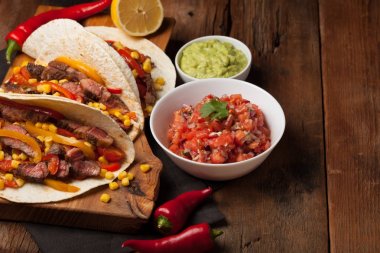 Mermer sığır eti, siyah Angus ve sebze eski rustik masada üç Meksikalı Taco. Soslar guacamole ve salsa kase ile Meksika yemek