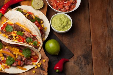 Mermer sığır eti, siyah Angus ve sebze eski rustik masada üç Meksikalı Taco. Soslar guacamole ve kase salsa Meksika tabak. Kopya alanı ile Üstten Görünüm