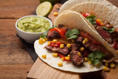 Mermer sığır eti, siyah Angus ve sebze eski rustik masada üç Meksikalı Taco. Soslar guacamole ve salsa kase ile Meksika yemek