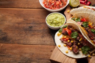 Mermer sığır eti, siyah Angus ve sebze eski rustik masada üç Meksikalı Taco. Soslar guacamole ve kase salsa Meksika tabak. Kopya alanı ile Üstten Görünüm