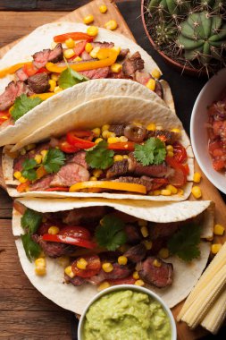 Mermer sığır eti, siyah Angus ve sebze eski rustik masada üç Meksikalı Taco. Soslar guacamole ve kase salsa Meksika tabak. Üstten Görünüm