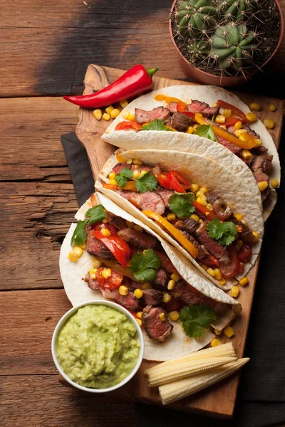 Trzy meksykańskie tacos z marmurkowym wołowiny, black Angus i warzywa na starej tabeli stylu rustykalnym. Meksykańskie danie z guacamole sosy i salsy w miskach. Widok z góry — Zdjęcie stockowe