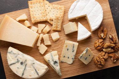 Ahşap plaka üzerinde peynir yemek tatma. Karanlık bir taş masada şarap ve romantik, peynir Şarküteri gıda. Üstten Görünüm