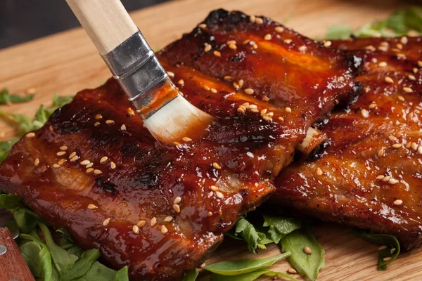 Primo piano chef spalmare salsa barbecue sulle costole con pennello — Foto Stock
