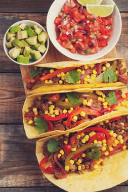 Kıyma ve karışımı sebze eski rustik masada üç Meksikalı Taco. Meksika yemeği kase ve avokado salsa sos ile. Sıcak ve baharatlı sokak gıda. Üstten Görünüm