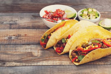 Kıyma ve karışımı sebze eski rustik masada üç Meksikalı Taco. Meksika yemeği kase ve avokado salsa sos ile. Sıcak ve baharatlı sokak gıda. kopya alanı ile