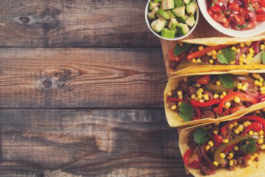 Kıyma ve karışımı sebze eski rustik masada üç Meksikalı Taco. Meksika yemeği kase ve avokado salsa sos ile. Sıcak ve baharatlı sokak gıda. Kopya alanı ile Üstten Görünüm