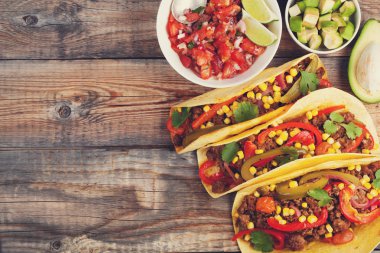 Kıyma ve karışımı sebze eski rustik masada üç Meksikalı Taco. Meksika yemeği kase ve avokado salsa sos ile. Sıcak ve baharatlı sokak gıda. Kopya alanı ile Üstten Görünüm