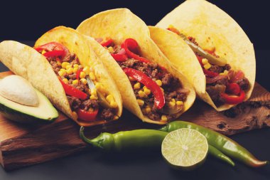 Üç Meksikalı tacos kıyma ve karışımı sebze siyah bir arka plan ile. Avokado Meksika tabak. Sıcak ve baharatlı sokak gıda