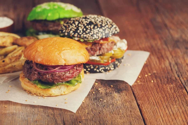 Set de tres mini hamburguesas caseras con carne de mármol y verduras sobre un antiguo fondo de madera. el concepto de comida chatarra y comida rápida. con espacio de copia — Foto de Stock
