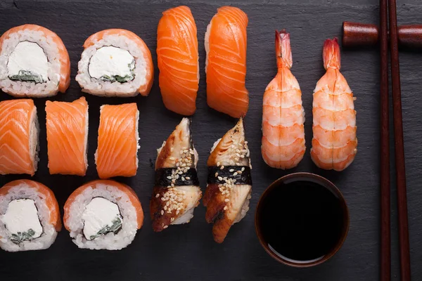 Közeli sushi beállítása sashimi lazac, garnéla, angolna és a sushi tekercs philadelphia szolgált a kő pala. Szemközti nézet — Stock Fotó