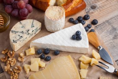 Ahşap plaka üzerinde peynir yemek tatma. Ahşap rustik masa üzerinde şarap ve romantik, peynir Şarküteri gıda. Üstten Görünüm