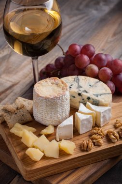 Ahşap plaka üzerinde peynir yemek tatma. Ahşap rustik masa üzerinde şarap ve romantik, peynir Şarküteri gıda.