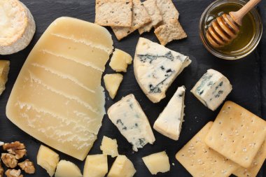 Koyu taş tabakta peynir tadı. Şarap ve romantik randevu için yemek, siyah beton arka planda peynir şarküteri. Üst görünüm