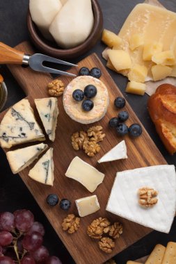 Koyu taş tabakta peynir tadı. Şarap ve romantik randevu için yemek, siyah beton arka planda peynir şarküteri. Üst görünüm