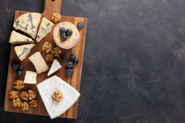 Koyu taş tabakta peynir tadı. Şarap ve romantik randevu için yemek, siyah beton arka planda peynir şarküteri. Kopyalama alanı olan üst görünüm