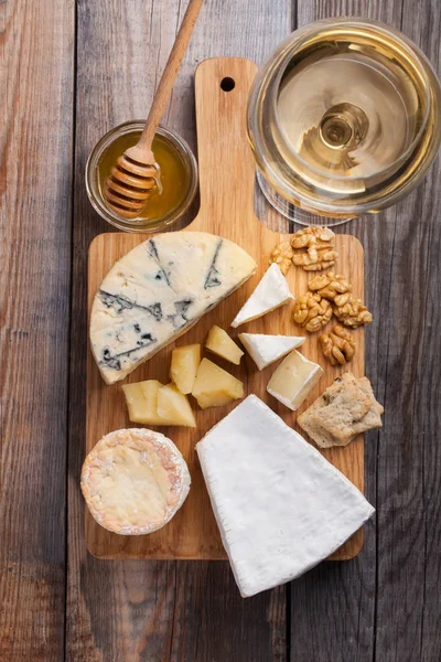 Tasting cheese dish on a wooden plate. Food for wine and romantic, cheese delicatessen on a wooden rustic table. Top view