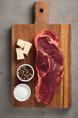 Ham sığır eti biftek vintage ile mermer eski taş zemin üzerine beyaz çatal bıçak takımı. Bir ahşap tahta üzerinde et parçası. Biftek New York. Üstten Görünüm