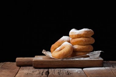 Siyah bir zemin üzerine pudra şekeri ile tatlı çörek. Ama eski ahşap masa kopya alanı ile zararlı gıda Tasty