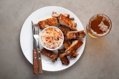 Barbekü sosu ve bal ile lahana turşusu ve bira beyaz tabakta Domuz kaburga ızgara. Taş Masa lambası bira yemek saati. Kopya alanı ile Üstten Görünüm