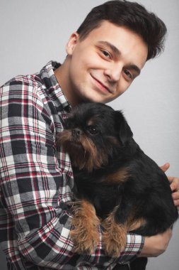 Portre portre yakışıklı genç hipster adam, onun iyi arkadaşım siyah köpek öpüşme açık renkli izole. Olumlu insan duyguları, yüz ifadesi, duygular