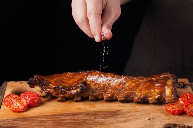 Şef tuz Domuz kaburga, yemeye hazır bir eski ahşap masanın üzerinde yatan sprinkles. Bir adam siyah bir arka plan kopya alanı ile bira için atıştıracak bir şeyler hazırlar