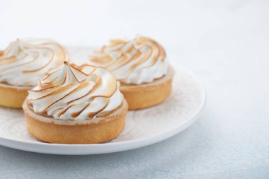 Taş masanın üzerinde vintage beyaz tabakta beze ile limon tartlets. Lezzetli tedavi üzerinde bir açık mavi renkli. Kopya alanı ile