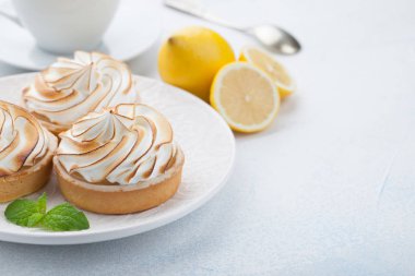 Limon beze vintage beyaz tabak ve bardak çay taş masanın üzerine ile tartlets. Lezzetli tedavi üzerinde bir açık mavi renkli. Kopya alanı ile
