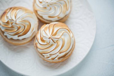 Beyaz vintage tabakta beze ile lezzetli limon tartlets. Tatlı ışık mavi bir arka plan üzerinde tedavi. Düz yatıyordu. Üstten Görünüm.