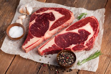 İki taze çiğ mermer et, kara Angus eti biftek eski bir rustik tabloda baharatlar ile. Ahşap arka plan üzerinde ham sığır eti.