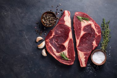 Ham taze et biftek antrikot kara Angus siyah mermer zemin üzerine mermer. Karanlık bir taş tabloda baharatlar ile sığır eti. Kopya alanı ile Üstten Görünüm