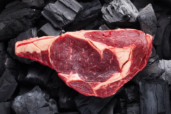 生鲜肉肉眼牛排配上黑色的木炭背景 — 图库照片