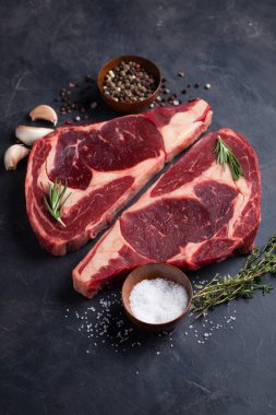 Ham taze et biftek antrikot kara Angus siyah mermer zemin üzerine mermer. Karanlık bir taş tabloda baharatlar ile sığır eti. Üstten Görünüm