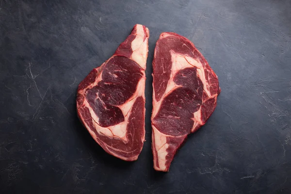 Čerstvé syrové mramorované maso Steak Ribeye Black Angus na černém mramorovém pozadí. Hovězí maso s kořením na temný kamenný stůl. Pohled shora — Stock fotografie