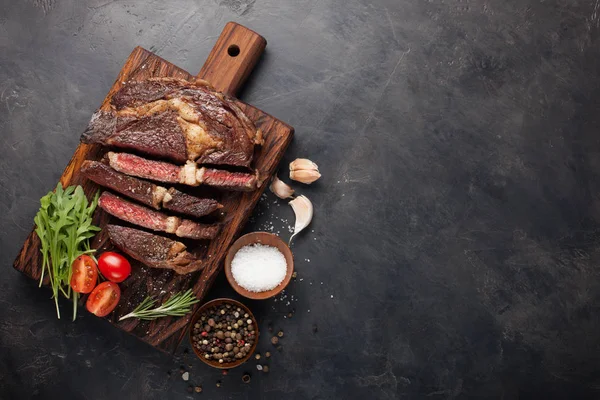 Bife de carne grelhada com vinho tinto, ervas e especiarias em um fundo de pedra escura. Vista superior com espaço de cópia para o seu texto — Fotografia de Stock