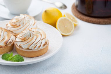 Limon beze vintage beyaz tabak ve bardak çay taş masanın üzerine ile tartlets. Lezzetli tedavi üzerinde bir açık mavi renkli. Kopya alanı ile