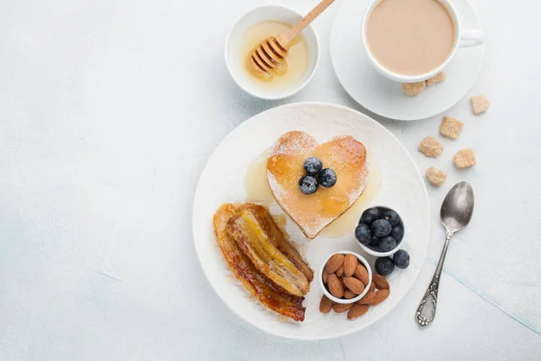 Egy halom finom palacsintát, méz, a kávé és a fekete áfonya, a világos kék háttér. Reggeli a Valentin-nap. Szemközti nézet másol hely — Stock Fotó
