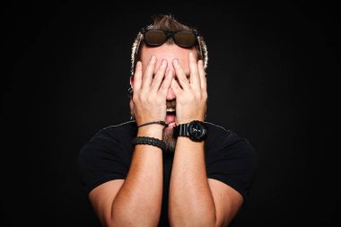 Studio siyah bir zemin üzerine ellerini yüzünü ve çığlıklar arkasına sakallı bir adam tutar