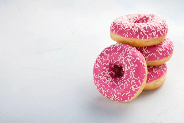 Donut. Sweet icing sugar food. Dessert colorful snack.Treat from delicious pastry breakfast. Bakery cake. Doughnut with frosting. Baked unhealthy round on a blue background. with copy space