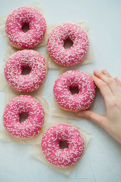 Donut. Sweet icing sugar food. Dessert colorful snack. Glazed sprinkles. Treat from delicious pastry breakfast. Bakery cake. Doughnut with frosting. A womans hand takes a donut. Top view
